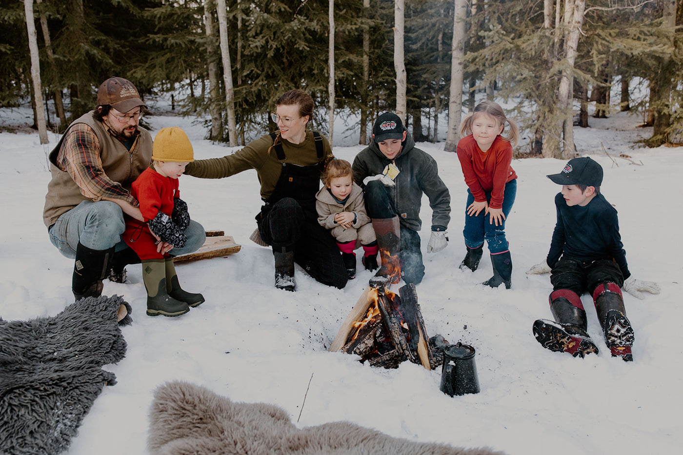 Kate Schat und ihre Familie sitzen im Schnee vor einem Lagerfeuer