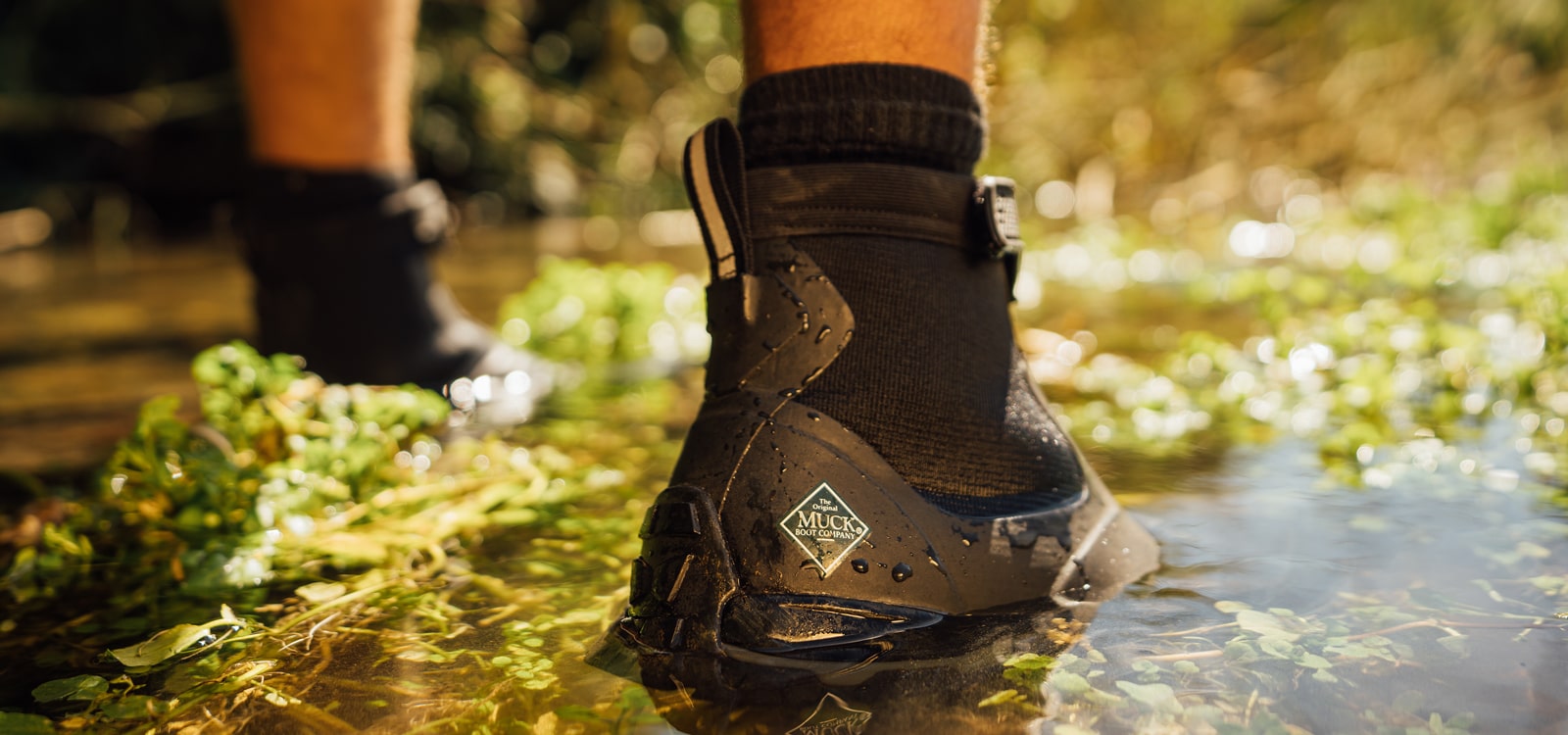 Nahaufnahme von einem Paar Muck Boots Apex Stiefel, die in Wasser stehen
