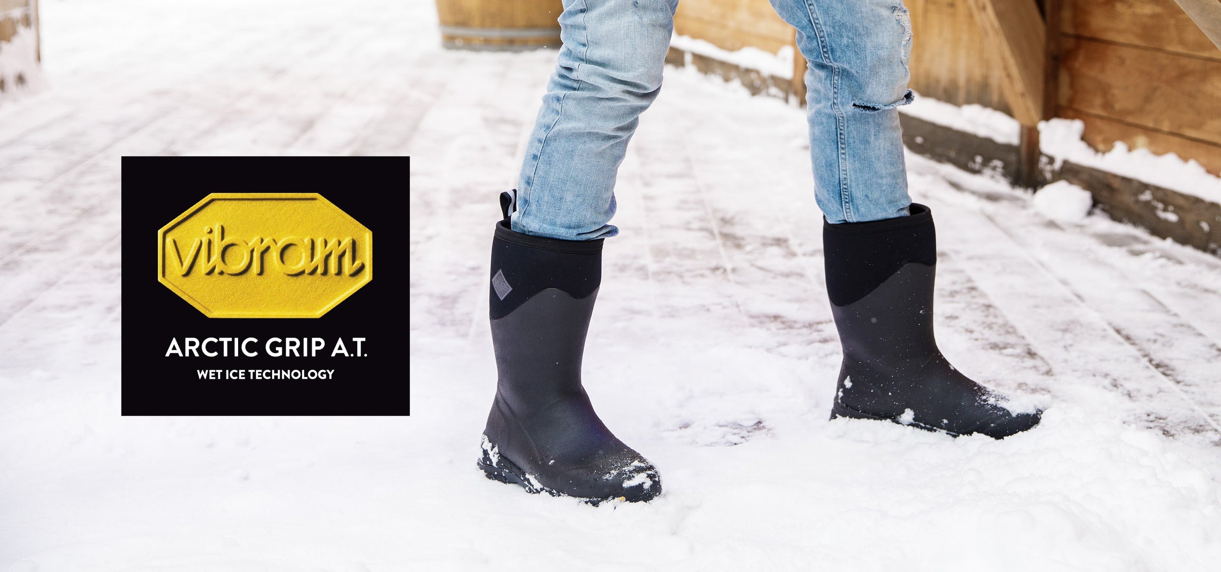 Nahaufnahme einer Person, die im Schnee steht und ein Paar Muck Boots trägt. Vibram-Logo auf der linken Seite