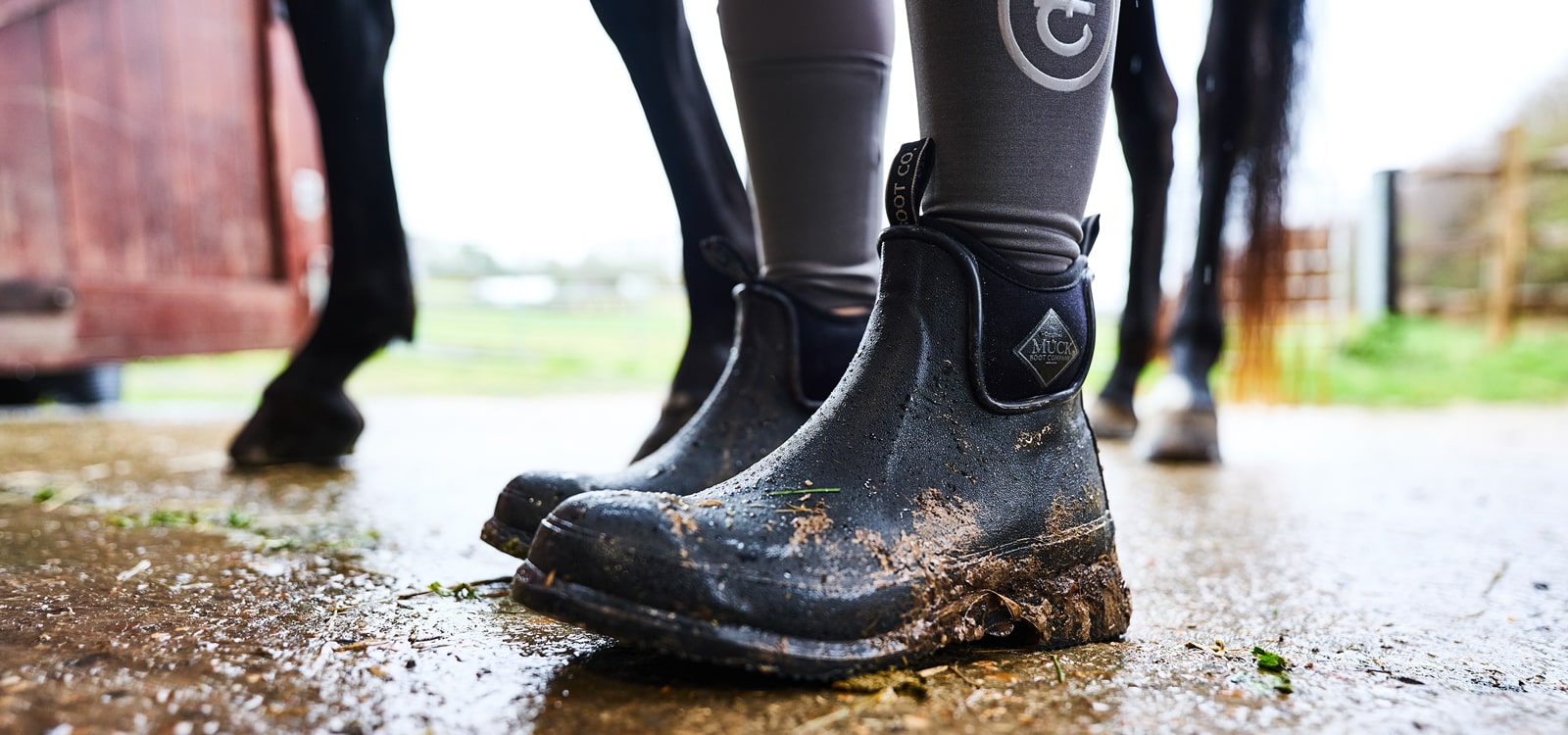 Nahaufnahme einer Person, die ein Paar mit Schlamm überzogene Muck Boots Unisex Wear Ankleboots trägt