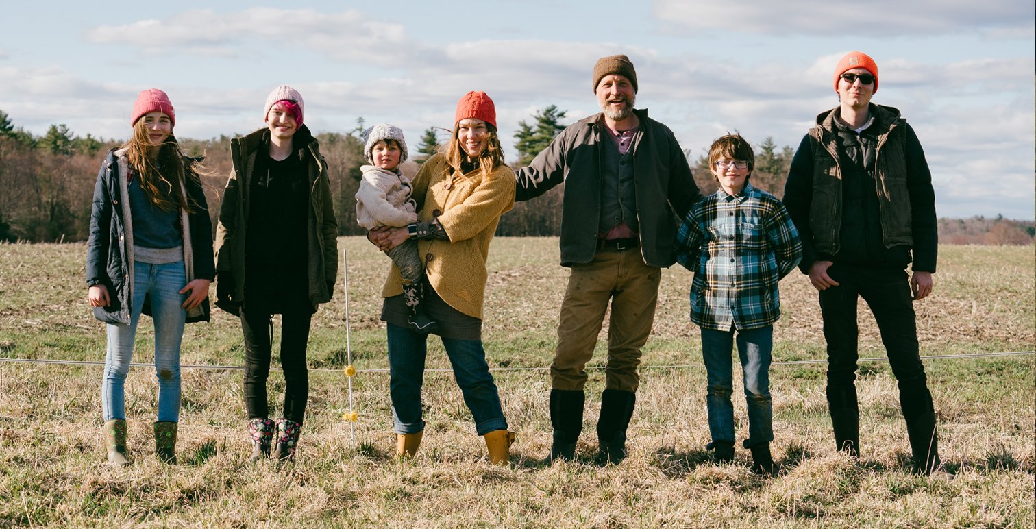 Eine Familie steht in einem Feld und trägt Winterkleidung und verschiedene Styles von Muck Boot